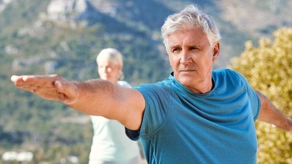 An older woman practicing balance near a kitchen counter at home