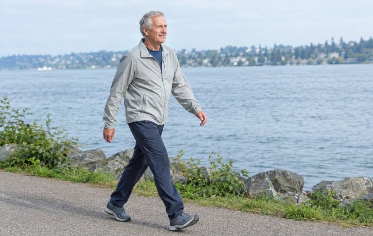 A man in his sixties walking along a waterfront path