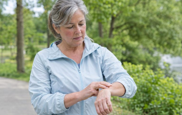 A woman in her sixties checking her pulse at the wrist during a walk